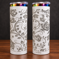 Two sides of one white 20 oz skinny tumbler with silver-gray engraved roses and vines and rainbow metallic rim